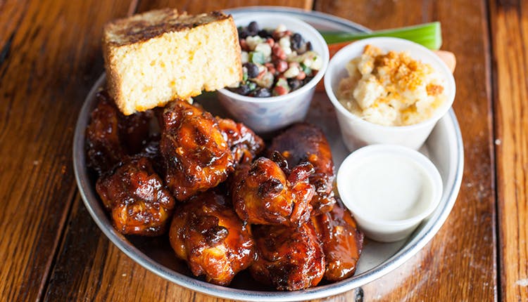 A plate of smoked chicken wings served with a variety of sides.