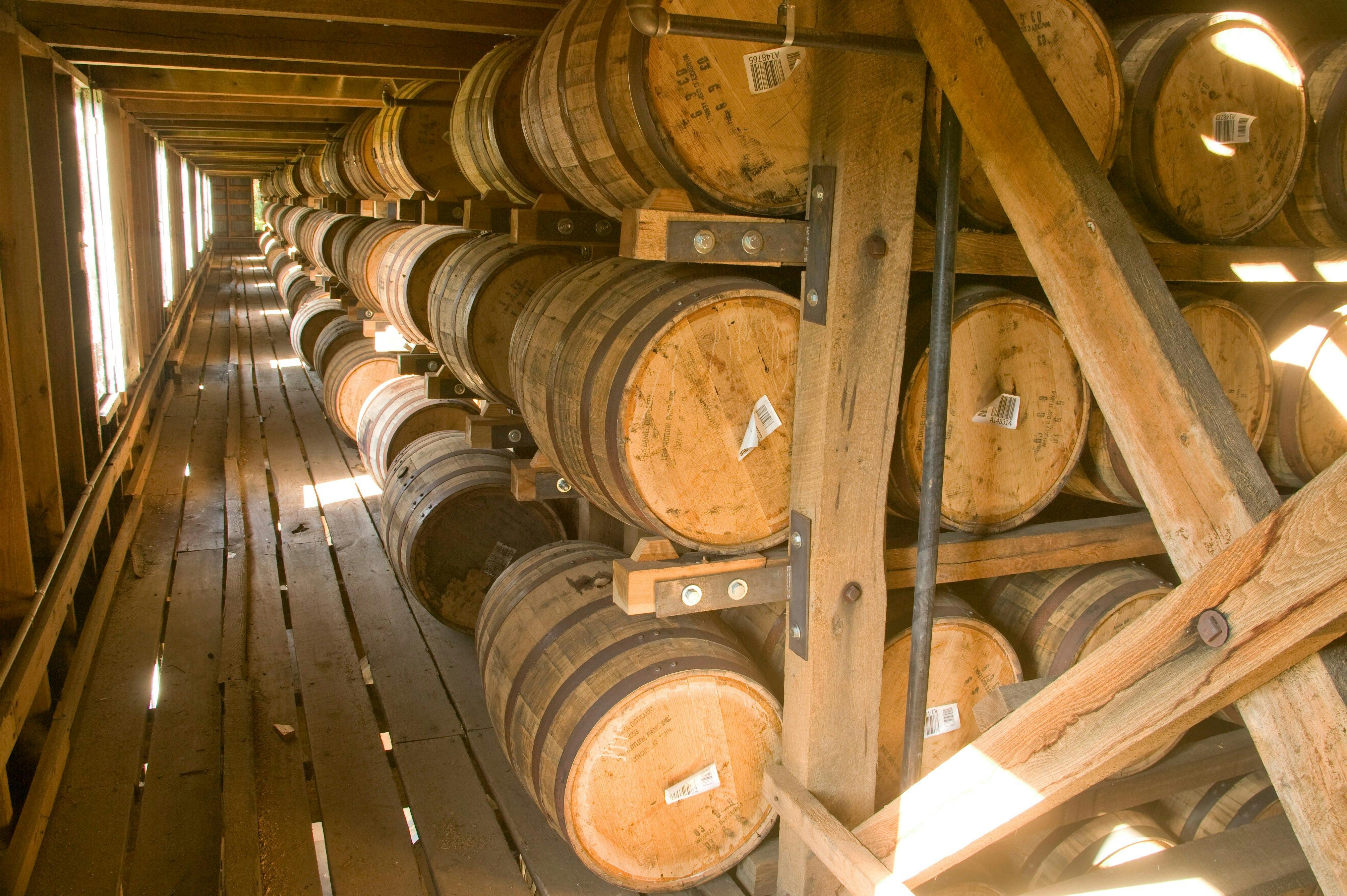 A rickhouse interior featuring long rows of wooden whiskey barrels stacked neatly on racks.