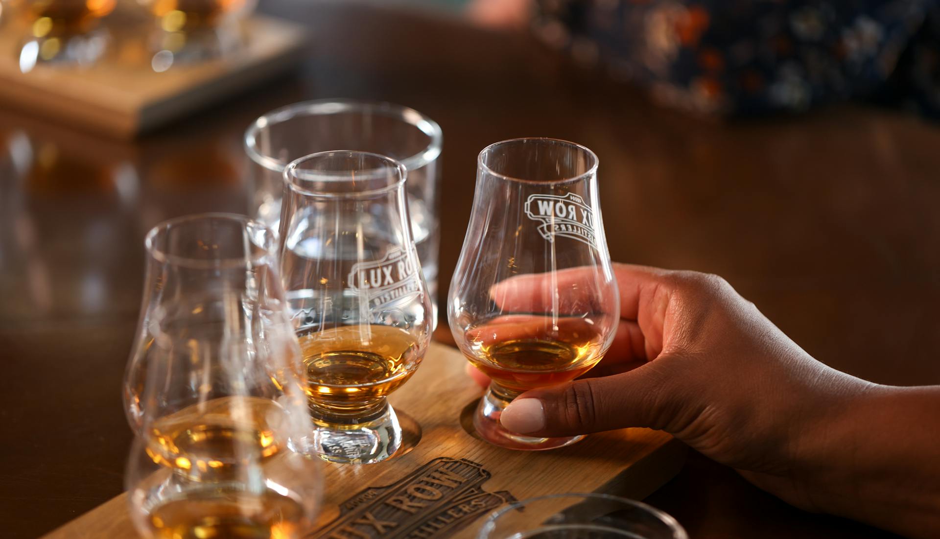 A set of tasting glasses filled with bourbon samples, arranged on a wooden tray at Lux Row Distilleries.