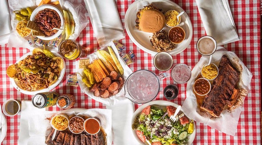 A table filled with a spread of plates featuring a variety of food from Charles Vergos' Rendezvous in Memphis.