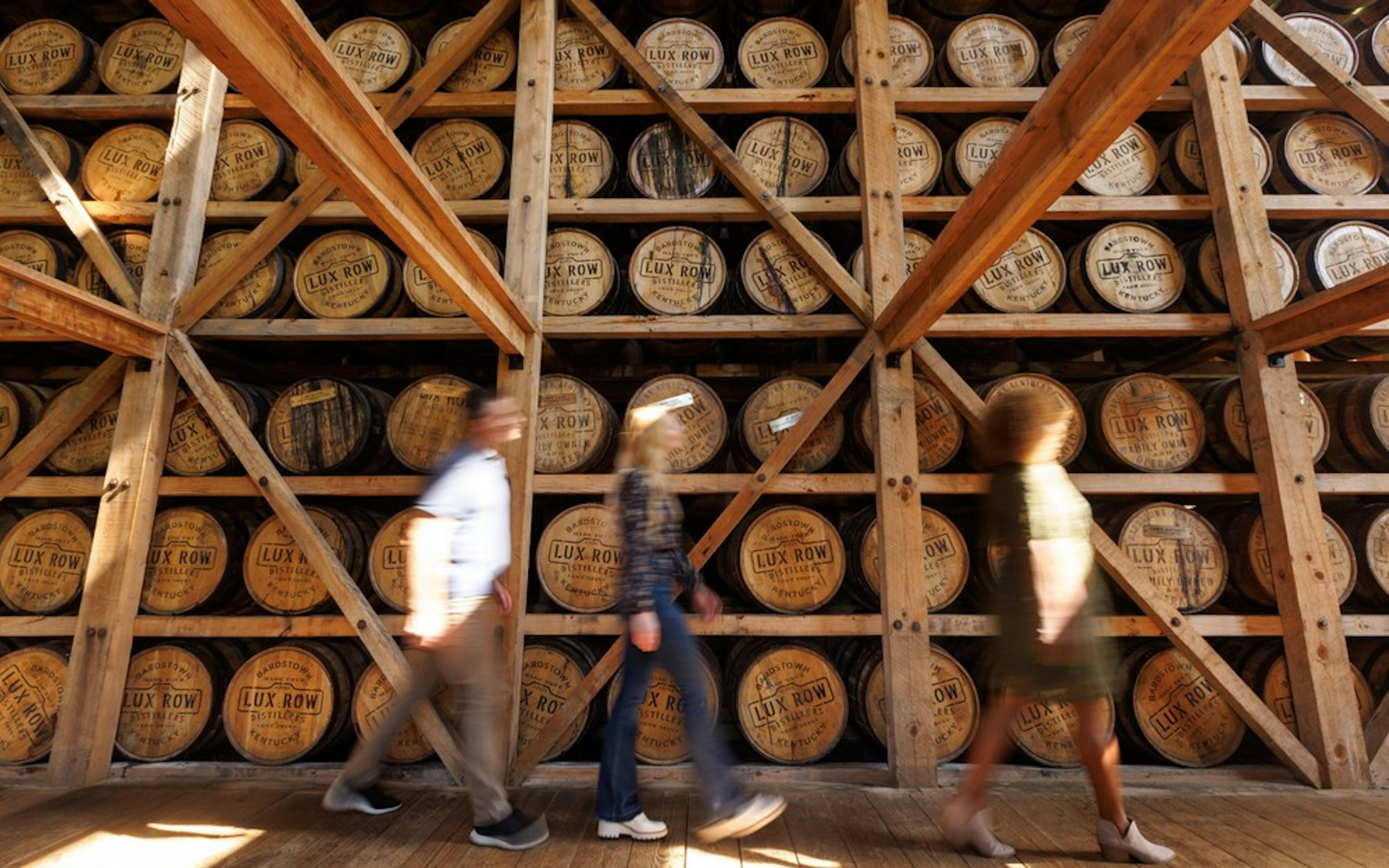 a group of 3 people on a mint julep tour exploring a rickhouse