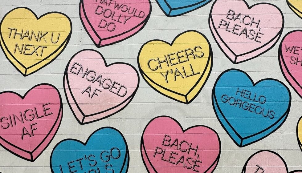 The "Candy Hearts Gulch" mural in Nashville is a vibrant, playful piece featuring oversized, pastel-colored candy hearts—each stamped with bachelorette-themed phrases.