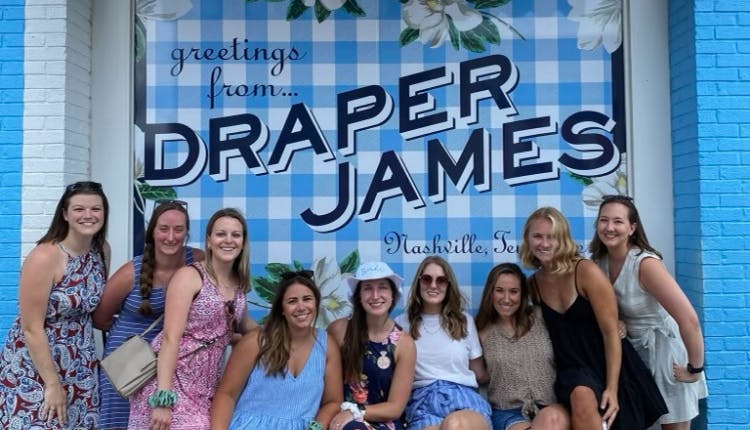 A group of women posing in front of a Draper James Mural in Nashville.