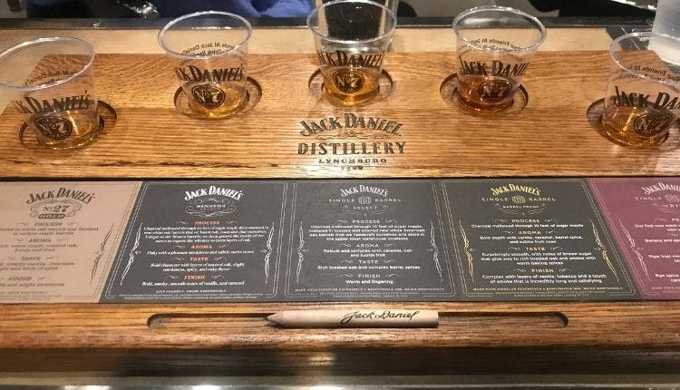 A set of drinking glasses with Jack Daniel's whiskey samples, accompanied by whiskey information cards on the table.