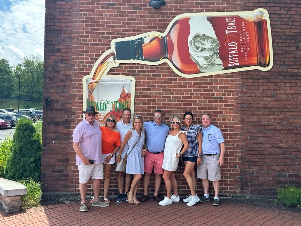 A group stand in front of a large Buffalo Trace logo.
