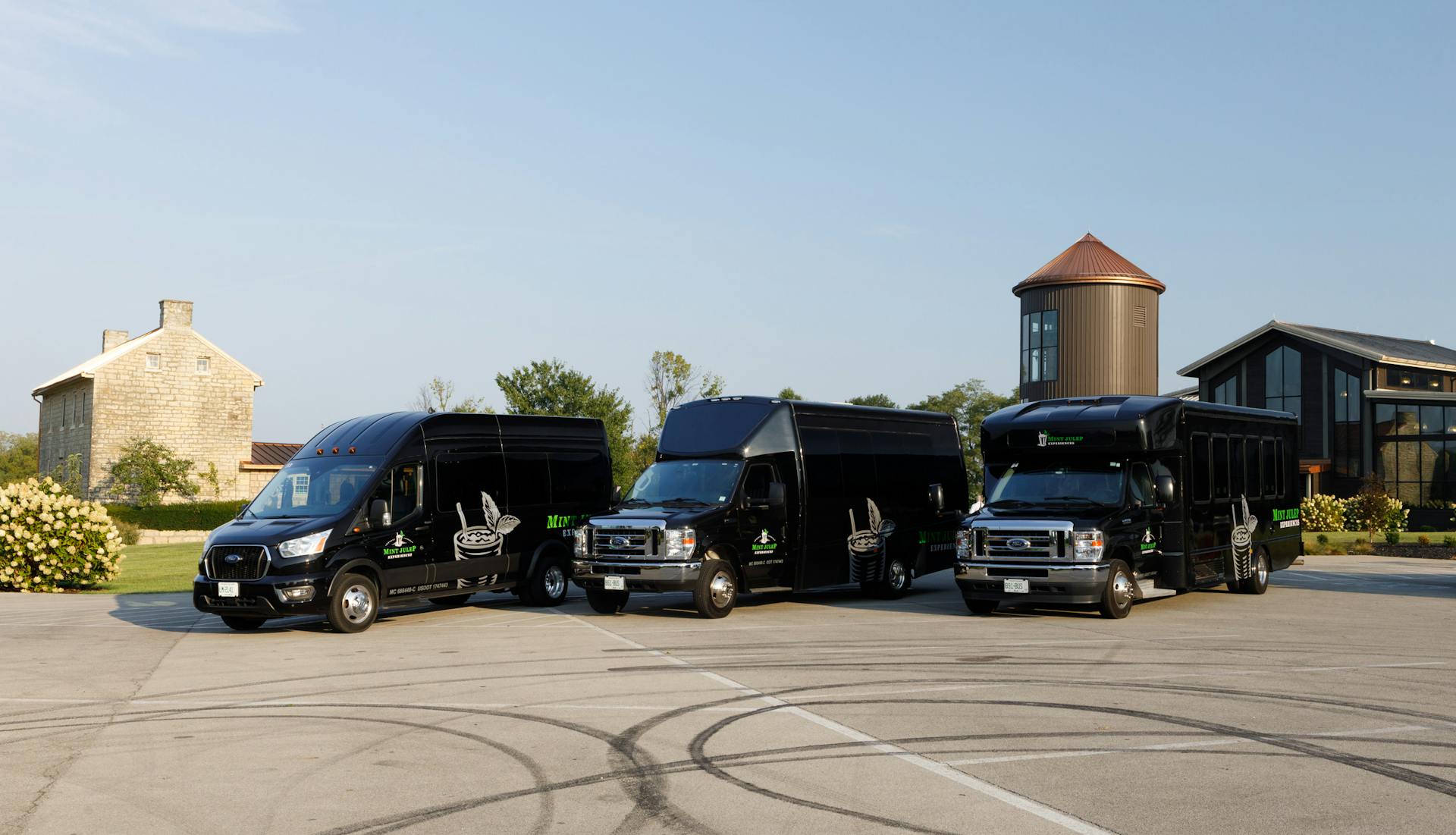 Three Mint Julep Experiences executive shuttles in front of a whiskey distillery.