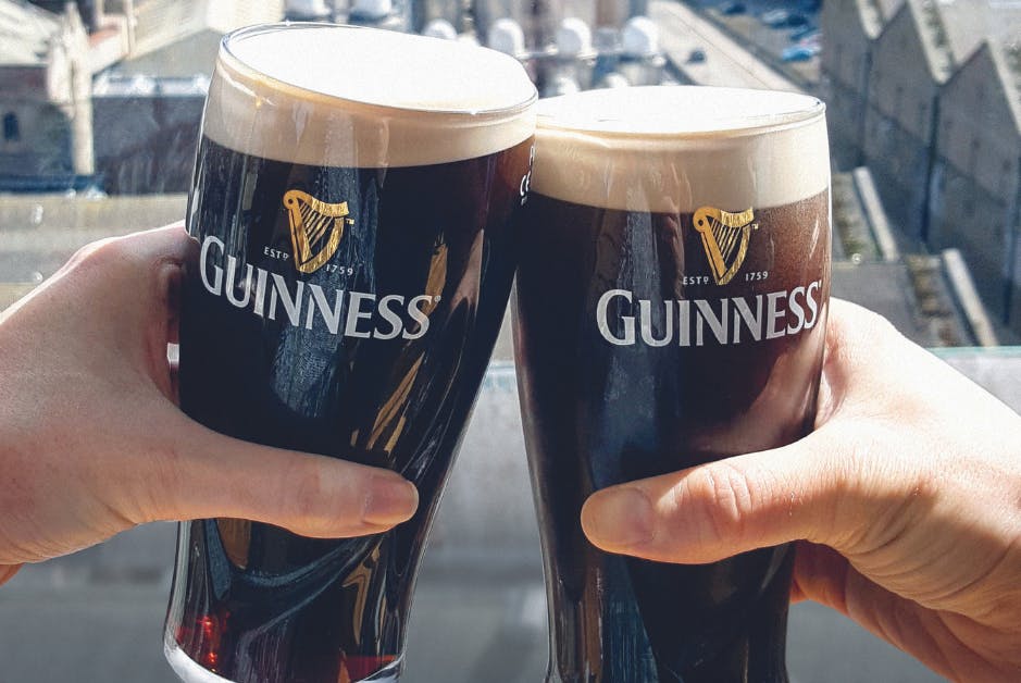 Two pints of Guinness being clinked together in a cheerful toast.