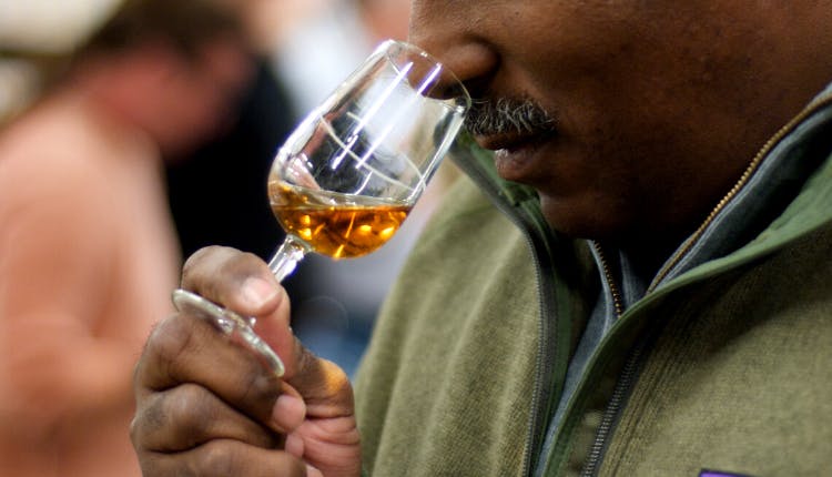 A man sniffing whiskey from a glass.