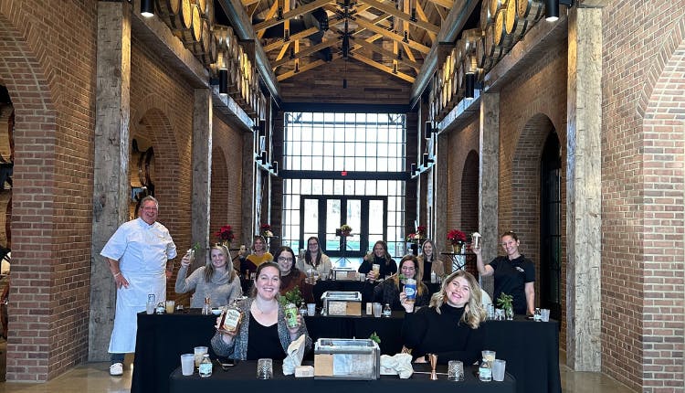 A group of Mixology Experience participants poses together, smiling and enjoying the moment after a fun class.