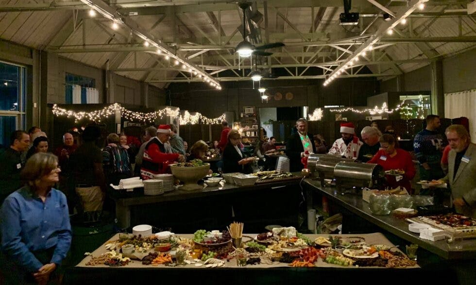 A company holiday party with a festive atmosphere, where attendees are serving themselves from a spread of assorted food.