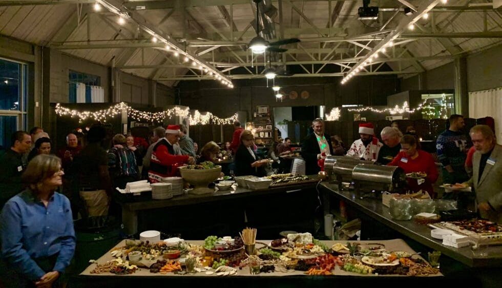 A company holiday party with a festive atmosphere, where attendees are serving themselves from a spread of assorted food.