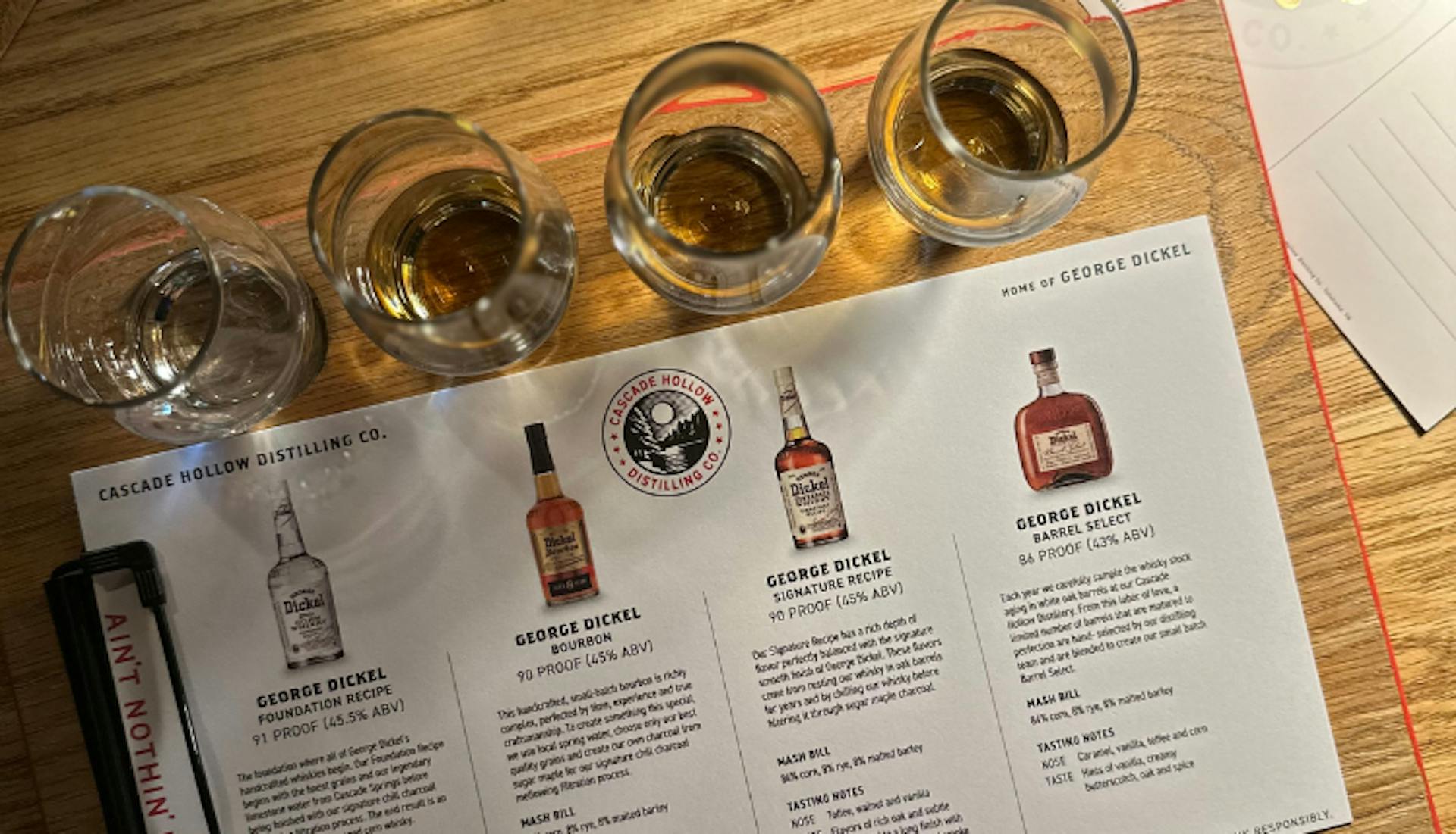 Glasses of bourbon accompanied by an information card, set up for a tasting experience at Cascade Hollow Distilling Co.