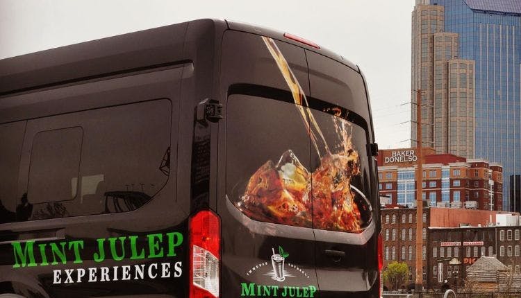 A Mint Julep Experiences luxury tour vehicle with the iconic Tennessee skyline in the background.