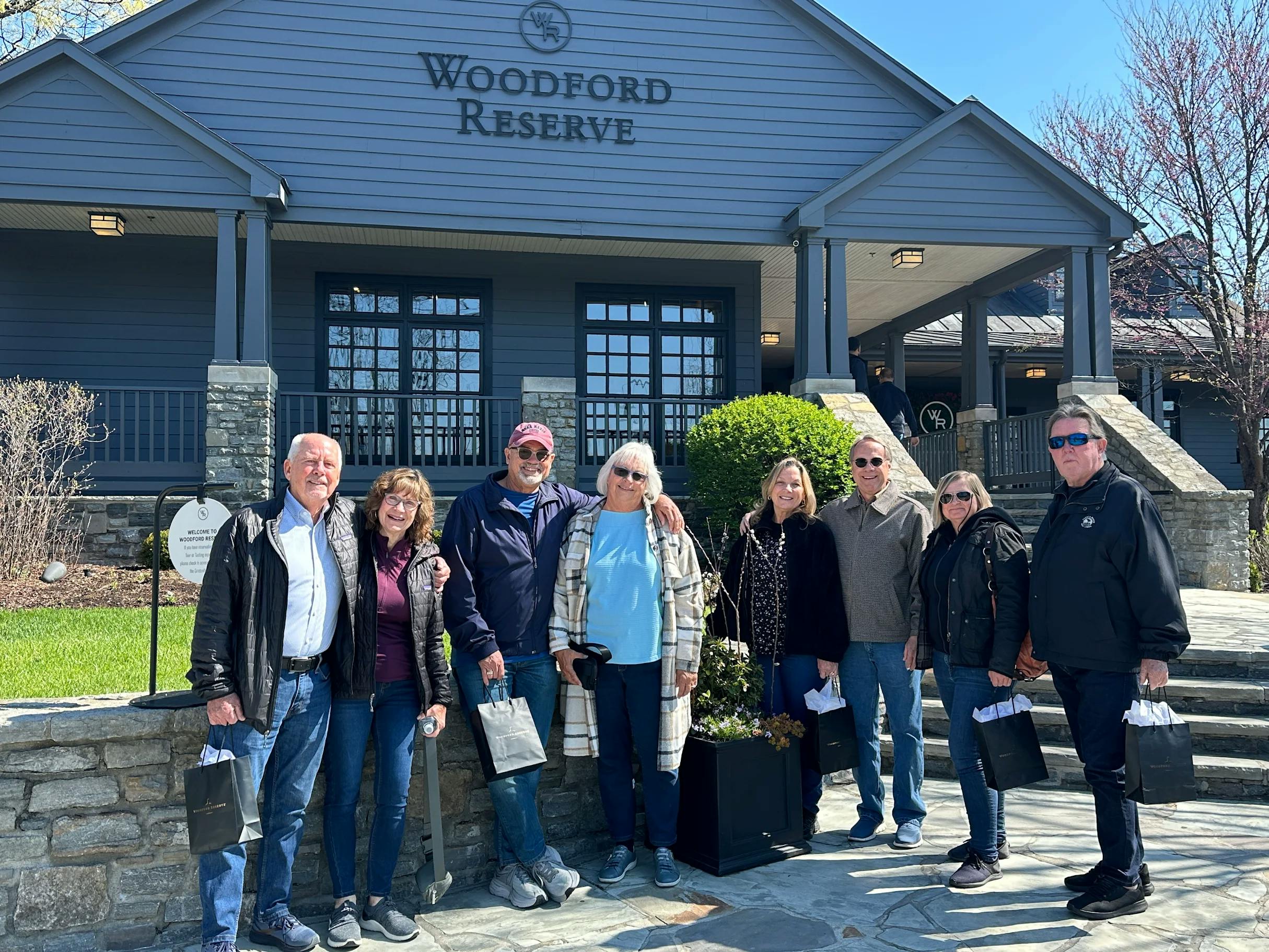 A group of Mint Julep Experience's guests post for a photo in front of Woodford Reserve