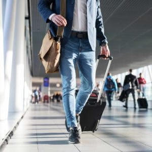 A traveler walking through the airport, pulling a suitcase and carrying a bag, capturing a moment of transit or arrival.
