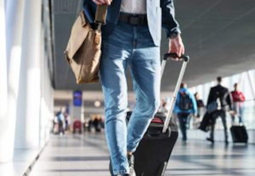 A traveler walking through the airport, pulling a suitcase and carrying a bag, capturing a moment of transit or arrival.