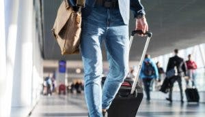 A traveler walking through the airport, pulling a suitcase and carrying a bag, capturing a moment of transit or arrival.