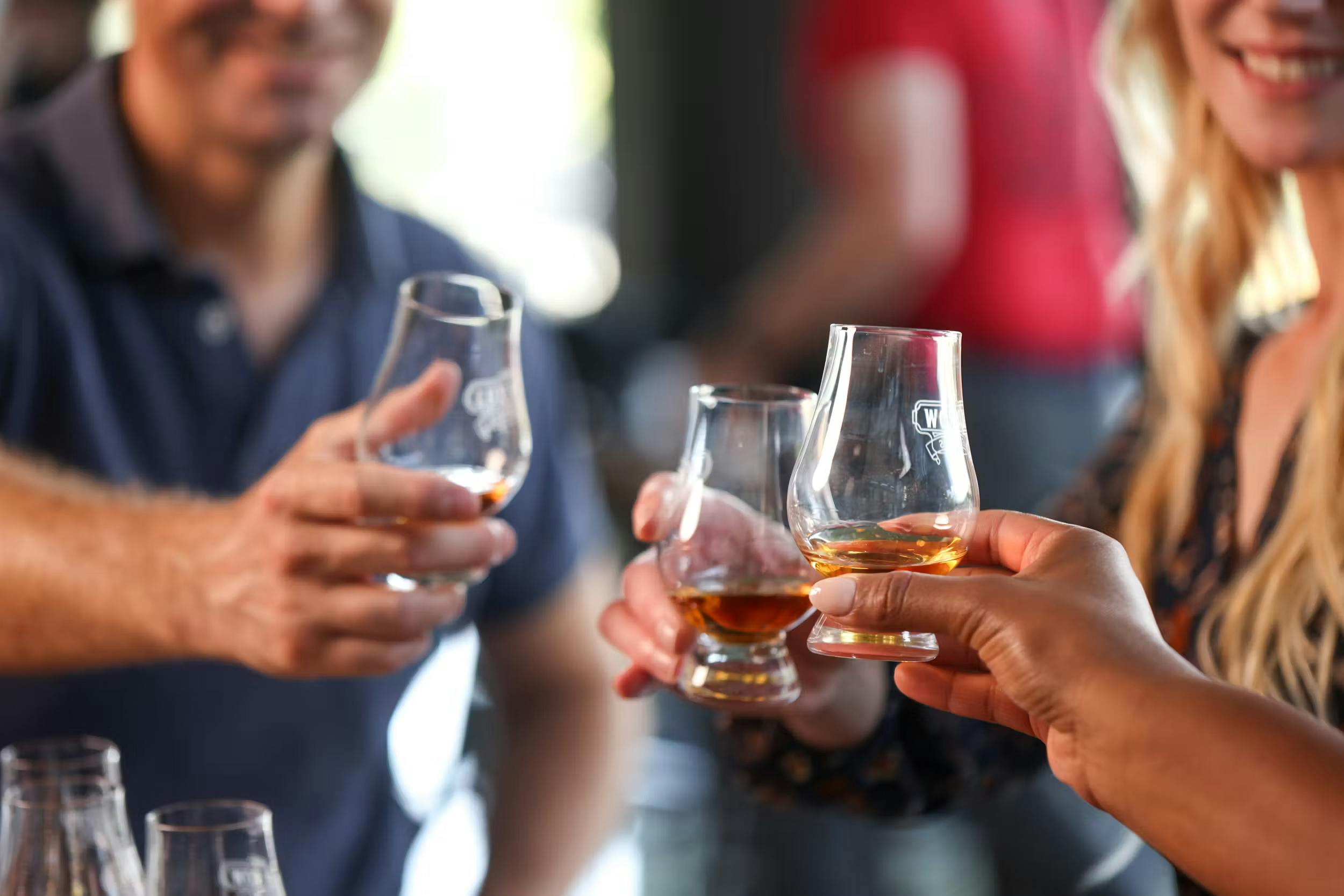 Three people enjoying their bourbon, each holding a glass and smiling as they savor the tasting experience.