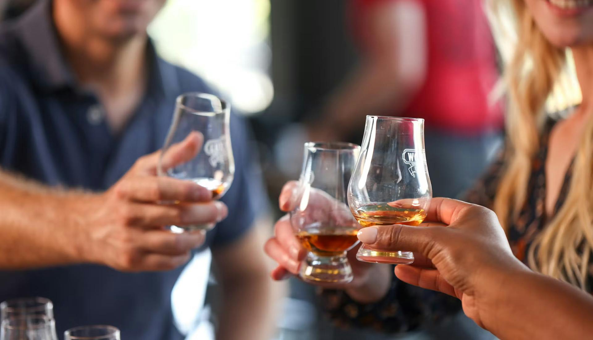 Three people enjoying their bourbon, each holding a glass and smiling as they savor the tasting experience.