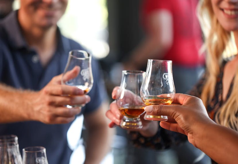 Three people enjoying their bourbon, each holding a glass and smiling as they savor the tasting experience.