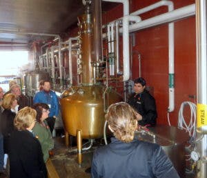 Learners at Moonshine University gathered around a copper still.