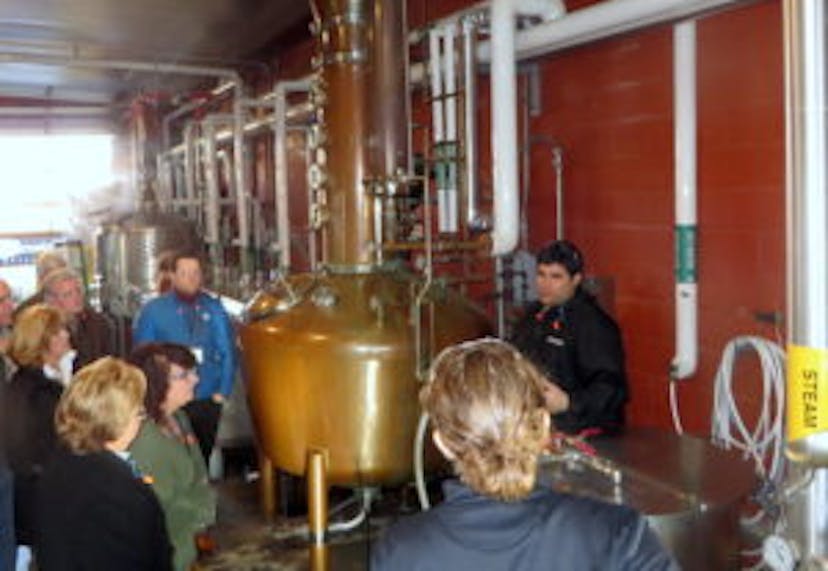 Learners at Moonshine University gathered around a copper still.