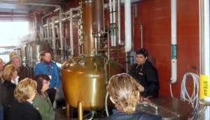 Learners at Moonshine University gathered around a copper still.