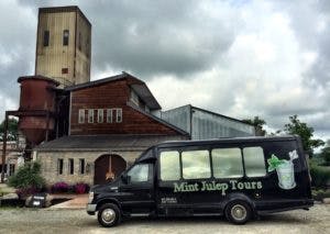 A Mint Julep Experiences vehicle in front of a distillery.