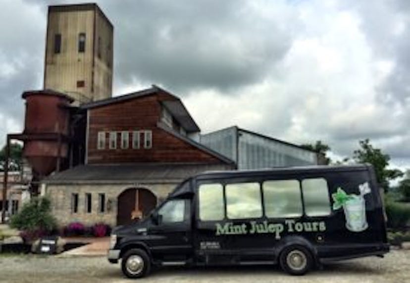 A Mint Julep Experiences vehicle in front of a distillery.
