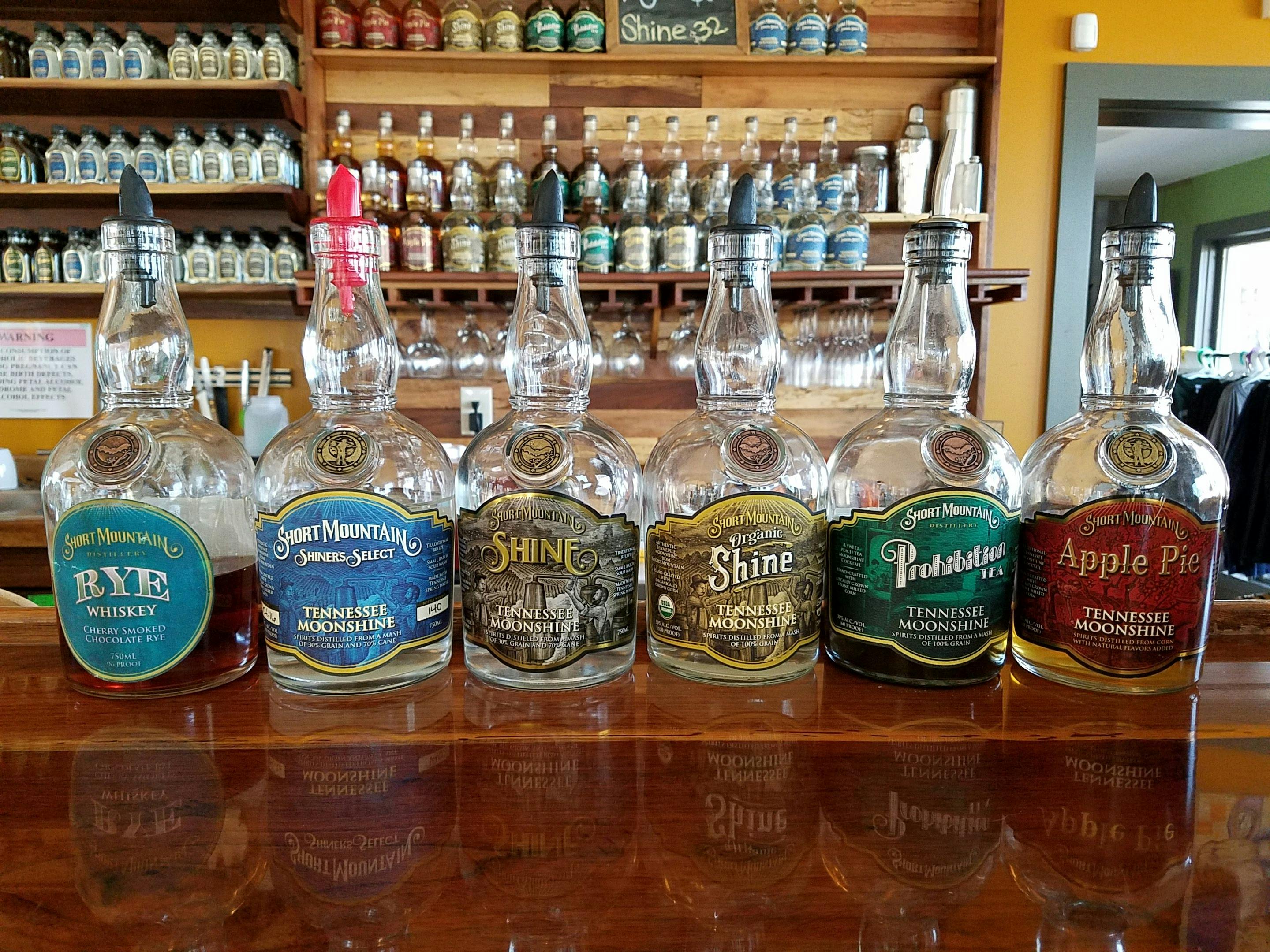 Bottles of Short Mountain Tennessee Moonshine and Rye Whiskey displayed on a bar counter.