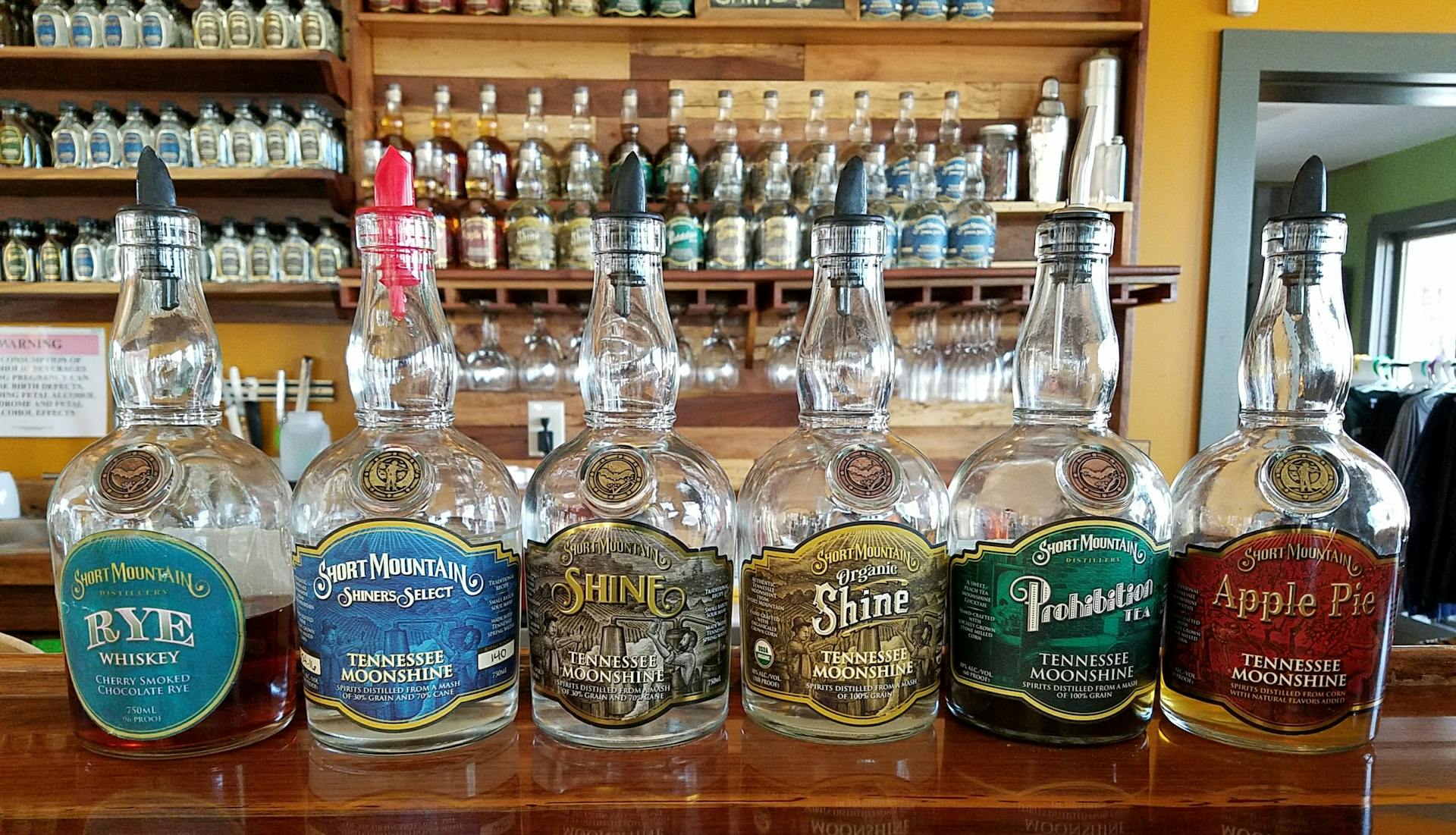 Bottles of Short Mountain Tennessee Moonshine and Rye Whiskey displayed on a bar counter.