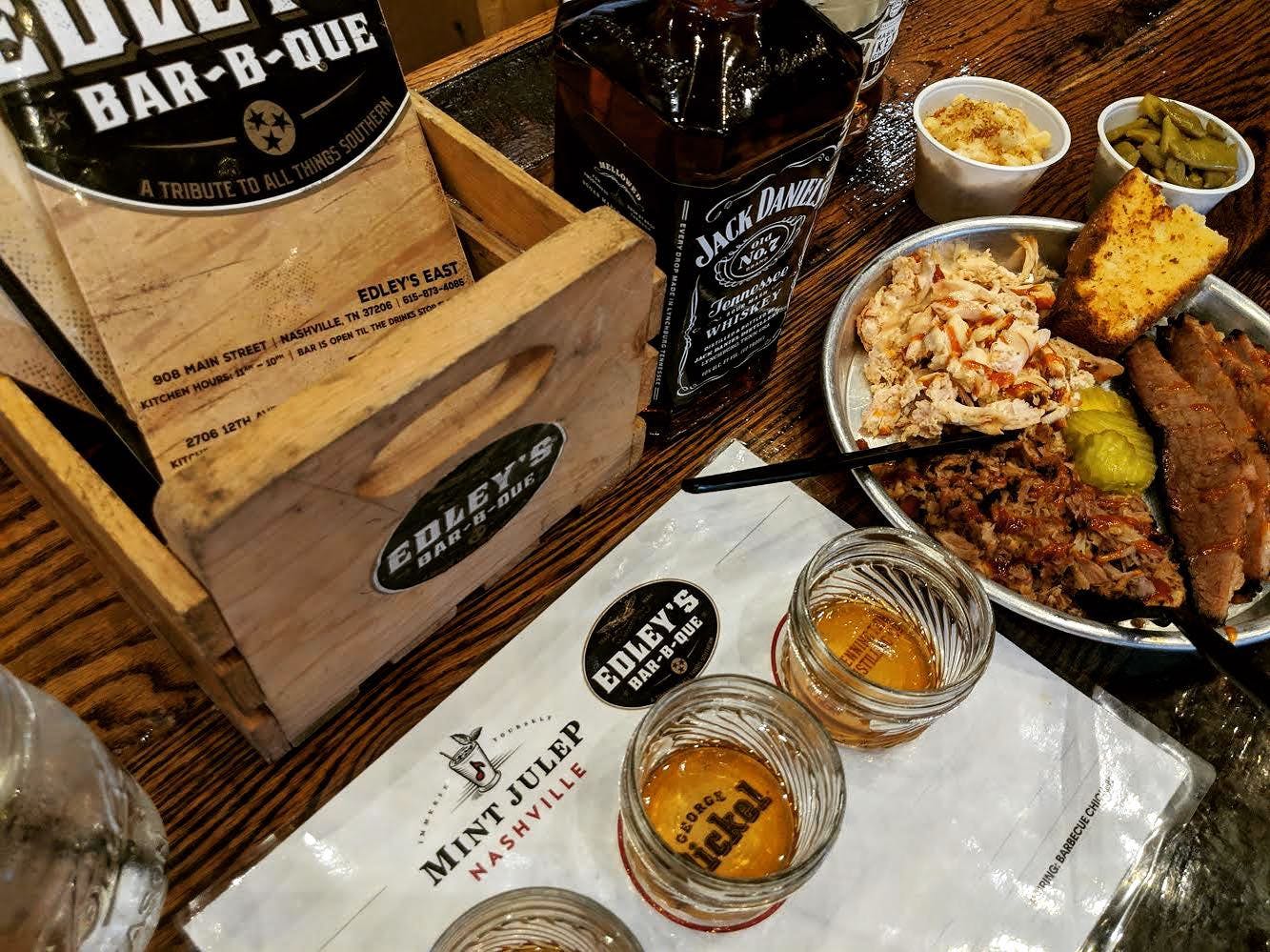 Plate of barbecue with sides, whiskey flights, and a bottle of Jack Daniel's at Edley's Bar-B-Que in Nashville