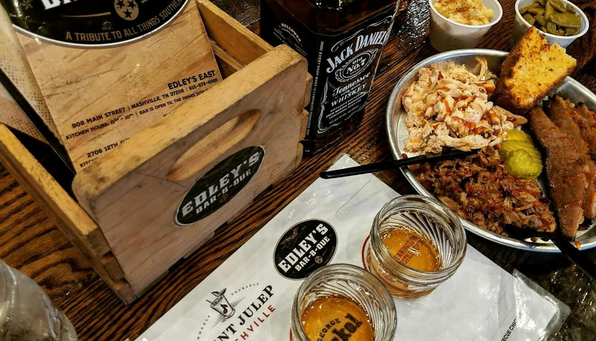 Plate of barbecue with sides, whiskey flights, and a bottle of Jack Daniel's at Edley's Bar-B-Que in Nashville.