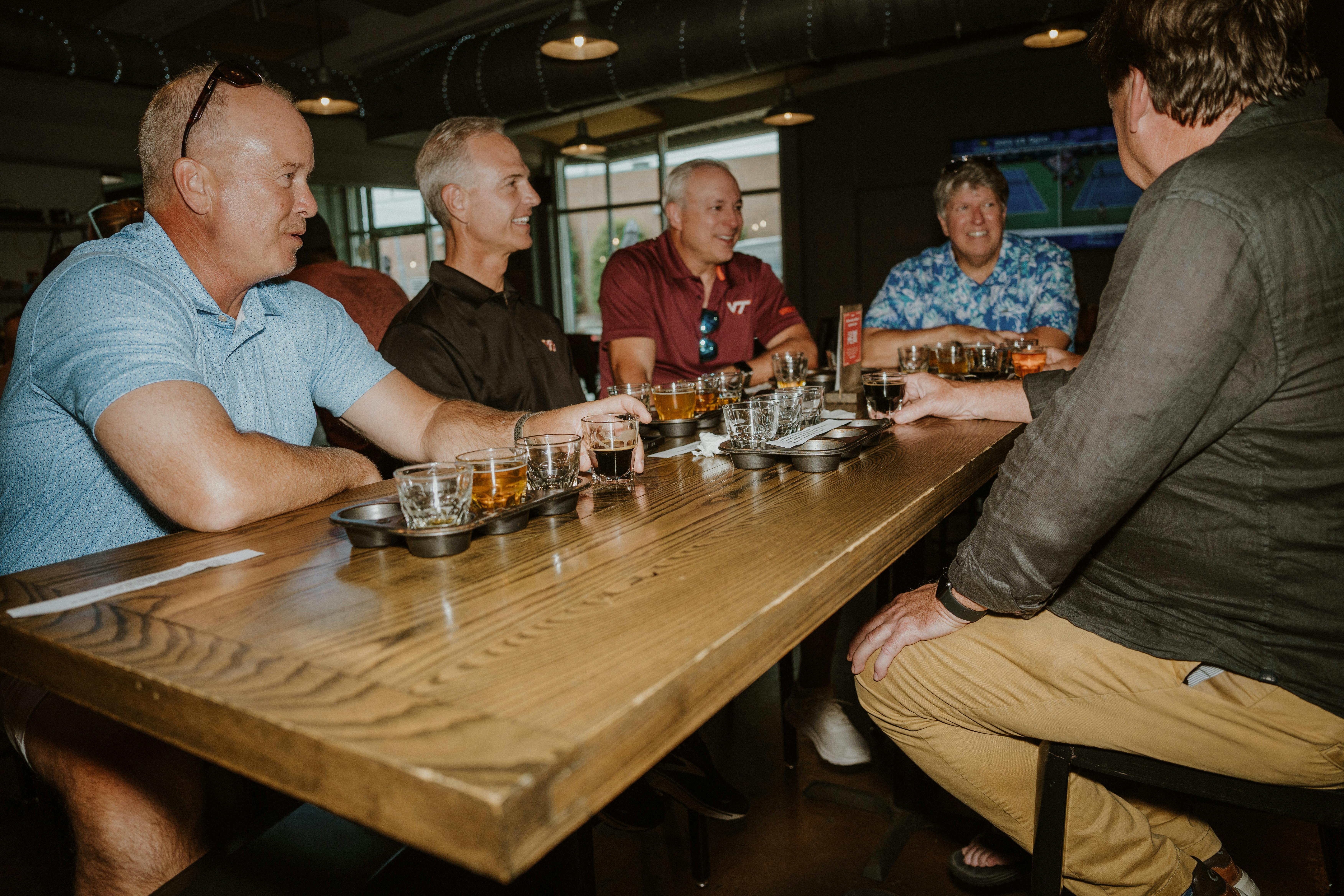 Group of men enjoying a whiskey tasting at a bar table.