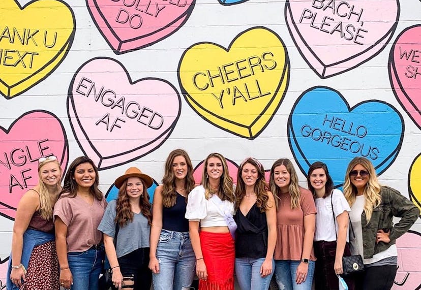 Group of women posing in front of a colorful mural with candy heart phrases in Nashville.