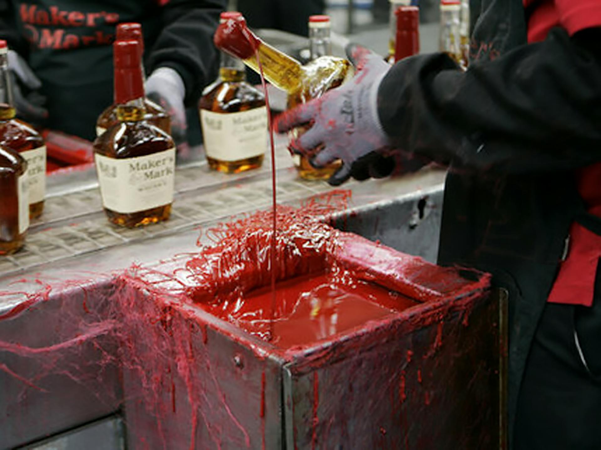 Behind the scenes at Maker's Mark Distillery showing how they dip the bottles to achieve their signature red wax seal