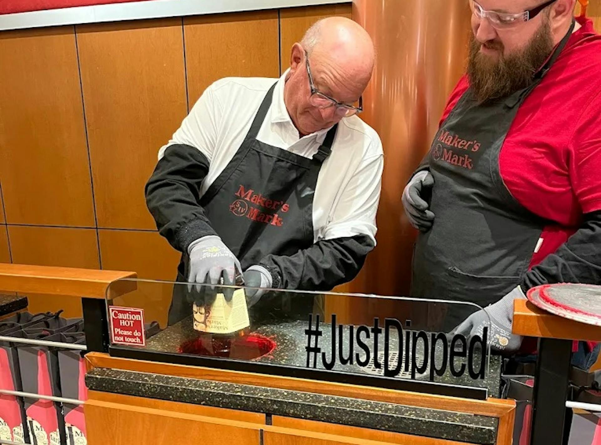 A Mint Julep Experience's tour attendee dipping their bourbon bottle at Maker's Mark distillery