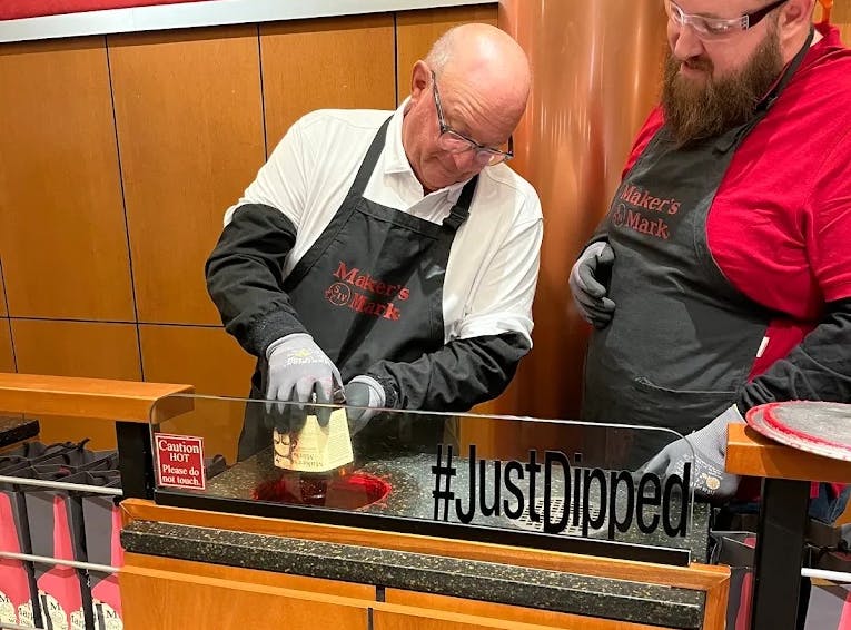A Mint Julep Experience's tour attendee dipping their bourbon bottle at Maker's Mark distillery