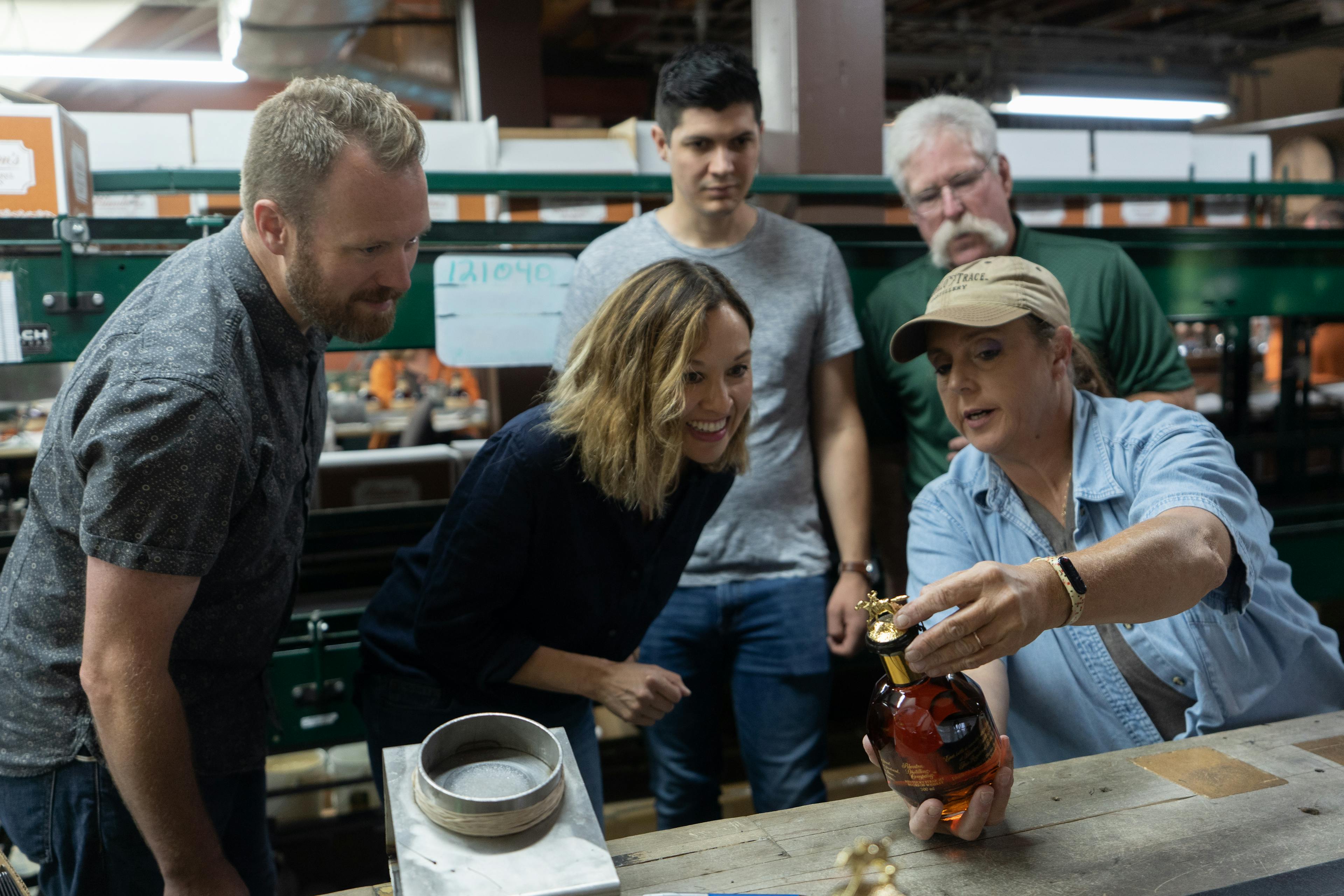 group of people on a buffalo trace tour with mint julep experiences looking at a bottle of blantons