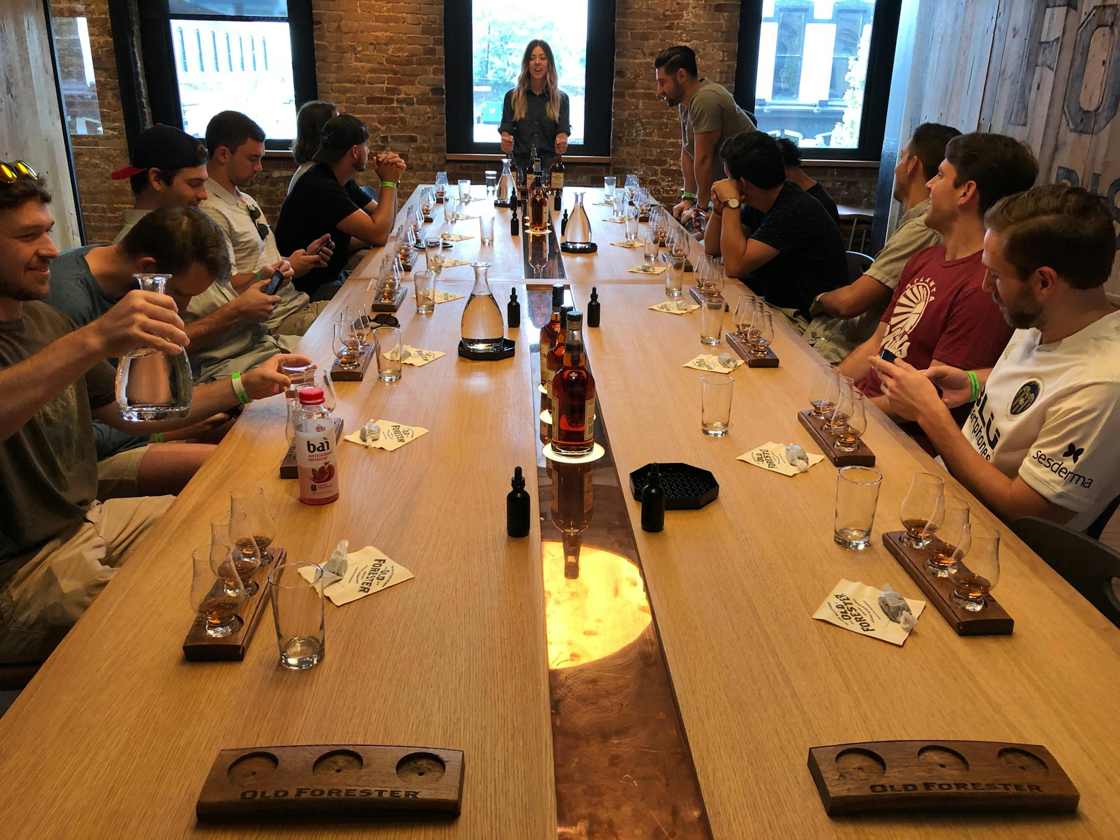 a group enjoying a guided tasting on an old forester distillery tour, hosted by mint julep experiences