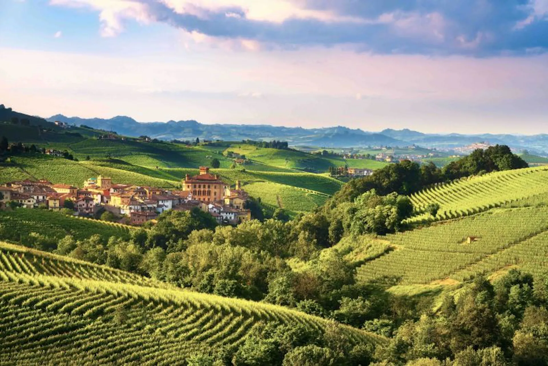 Rolling hills of Tuscany, Italy with blue skies and an old village in the background
