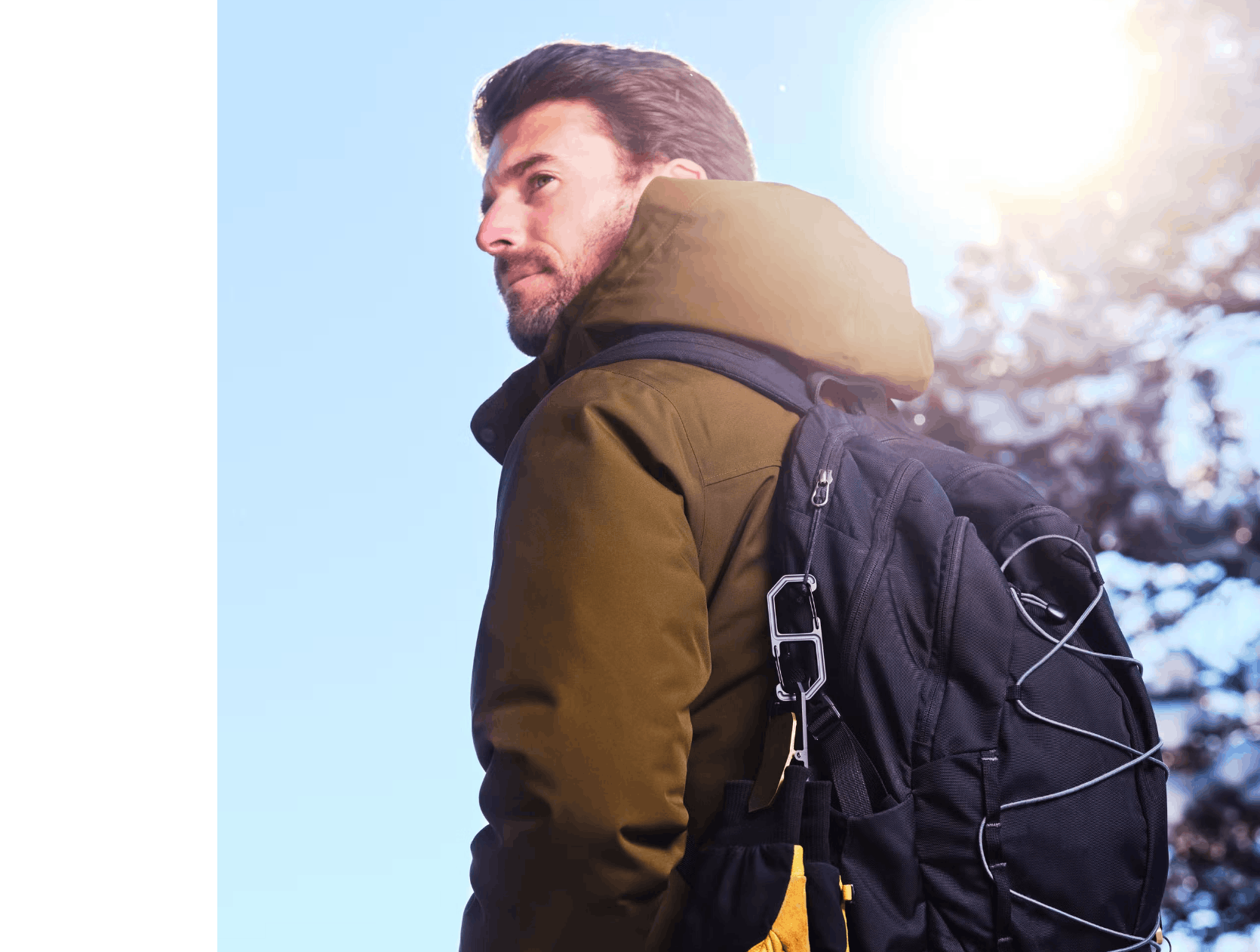 Man wearing a backpack with a carabiner holding winter gloves