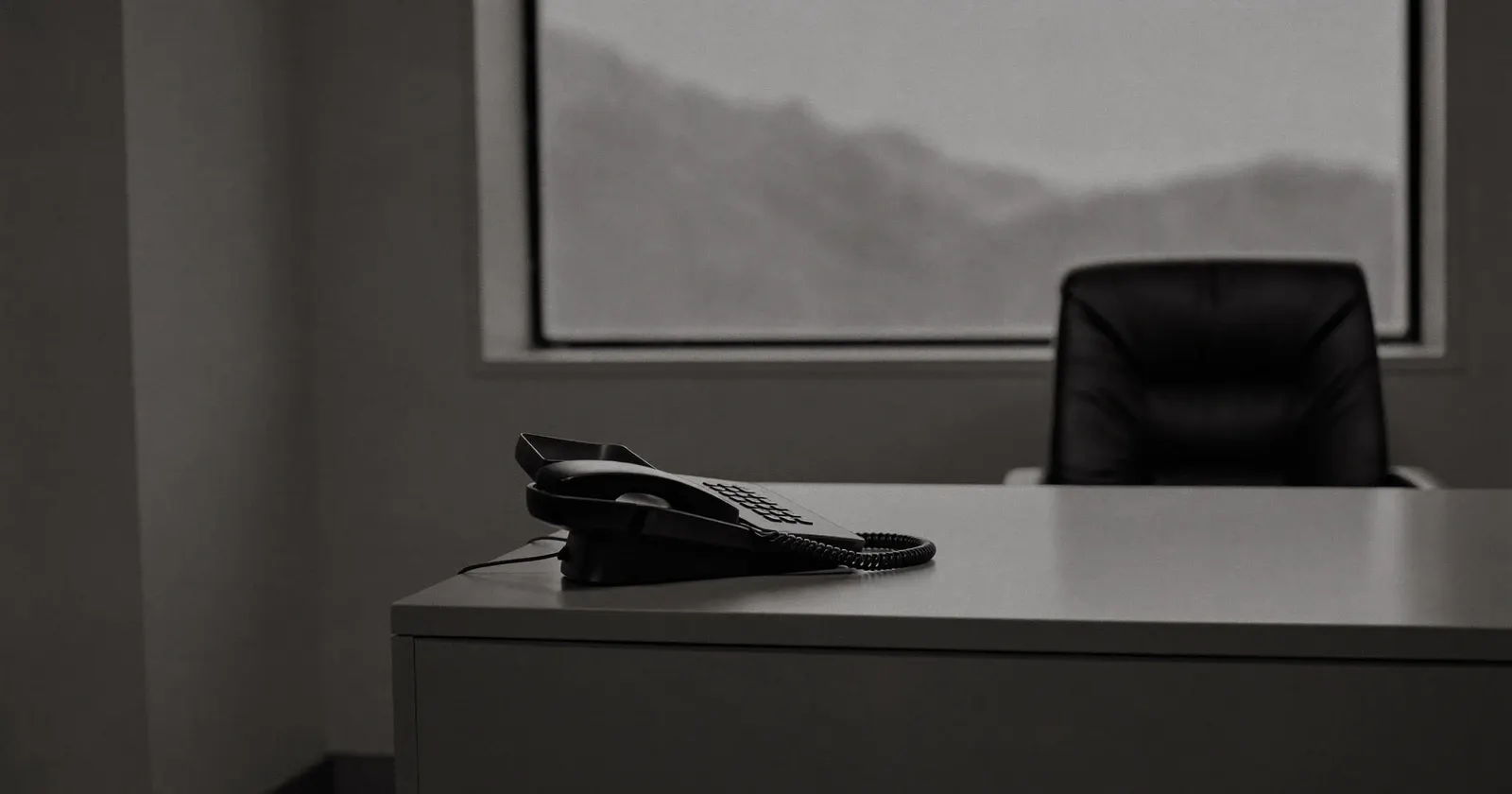 Office desk phone in morning light, a private equity buyer's call, black and white