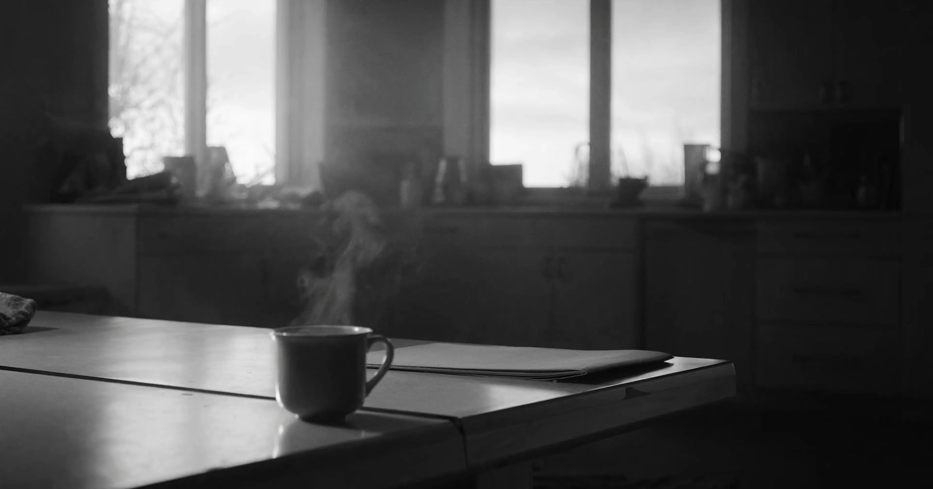 SME owner, morning coffee, closed document, contemplative black and white scene