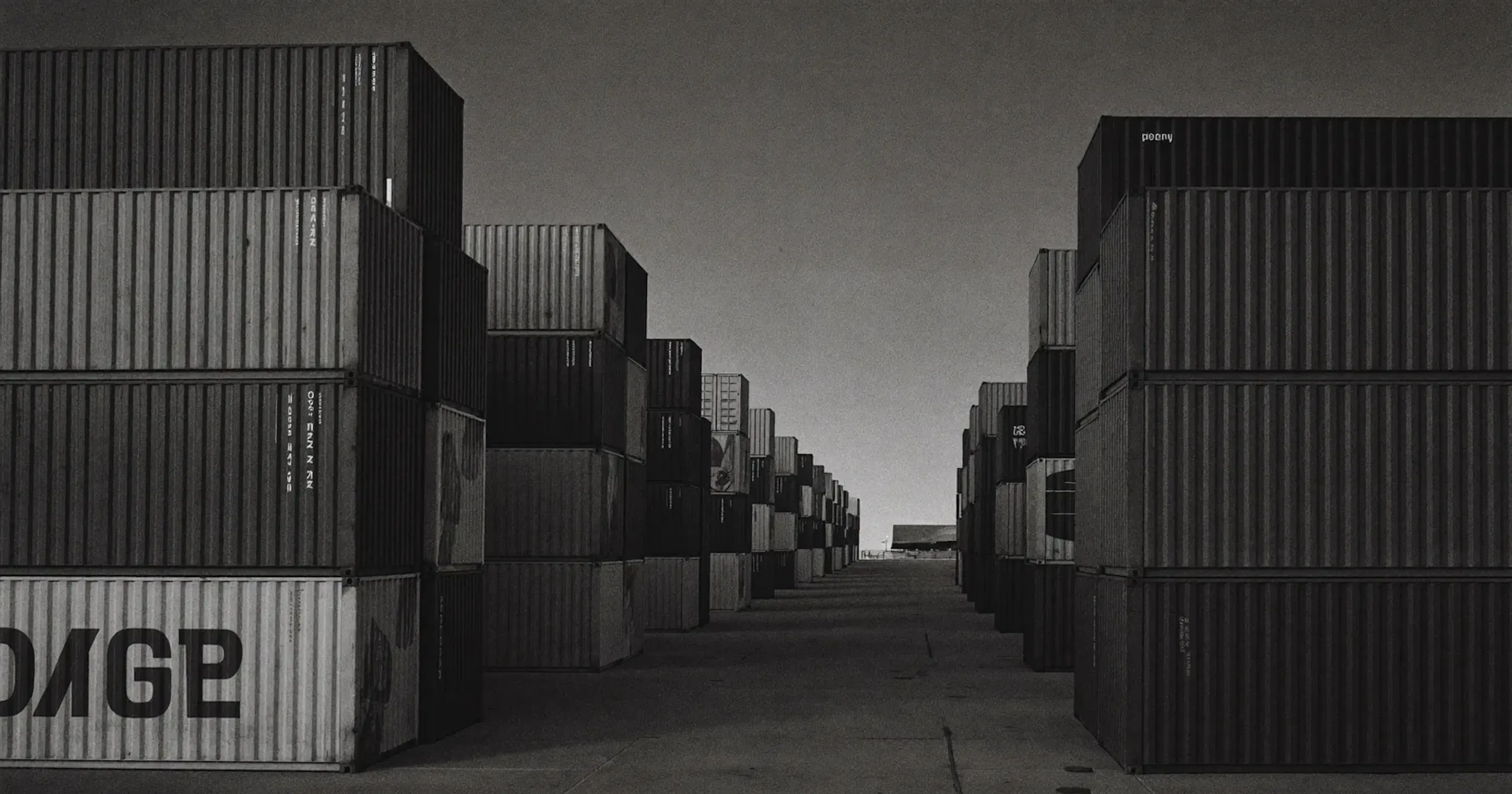 Cross-border loading dock at dusk with aligned shipping containers, structural levers against US tariffs, Canadian SME, sober black and white