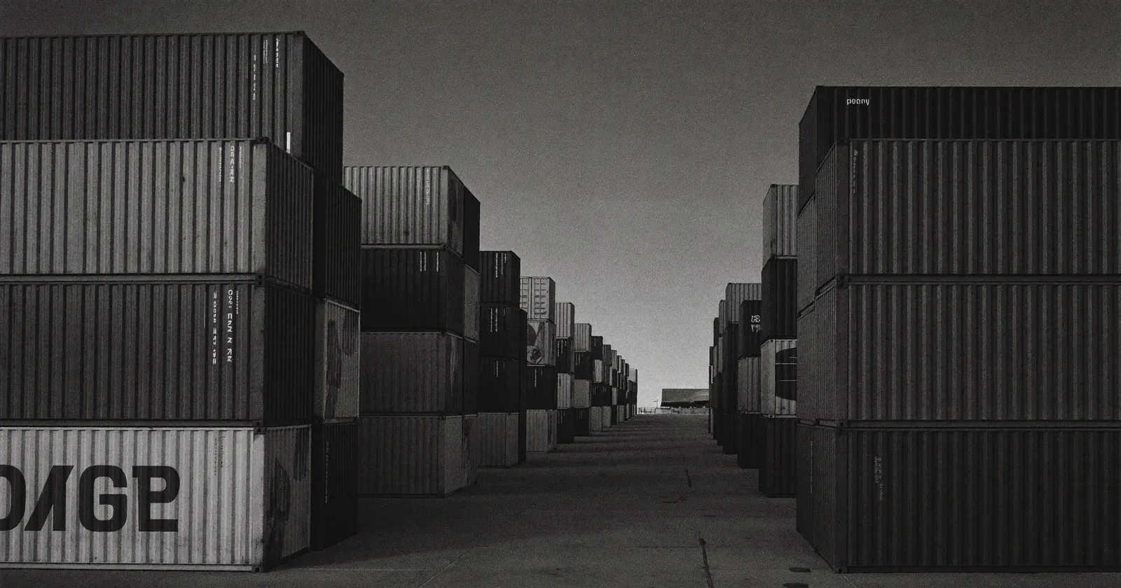 Cross-border loading dock at dusk with aligned shipping containers, structural levers against US tariffs, Canadian SME, sober black and white