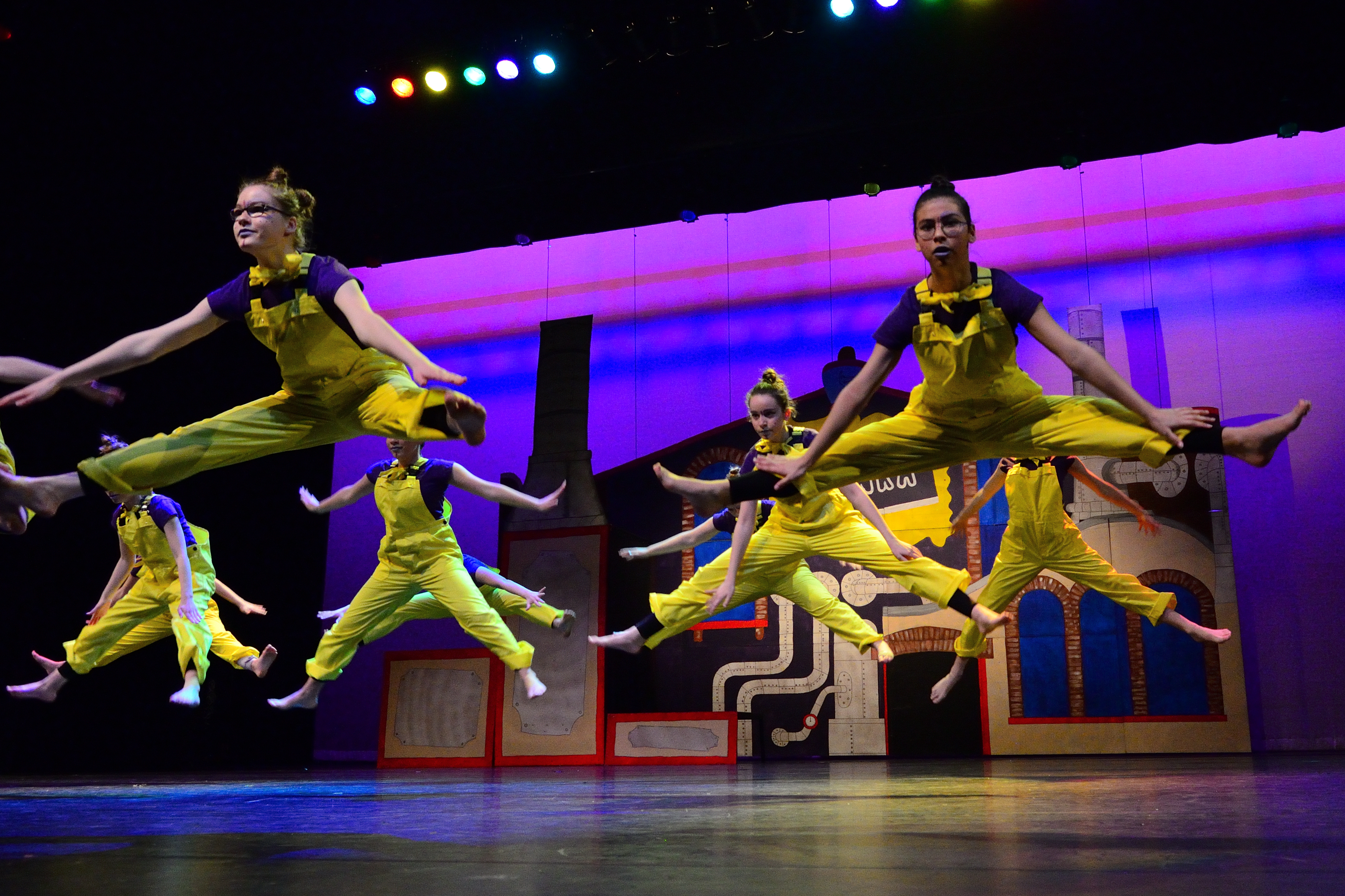 Dansers van Balletstudio Mirjam Ouwerkerk die een grote sprong maken tijdens een voorstelling in het theater.