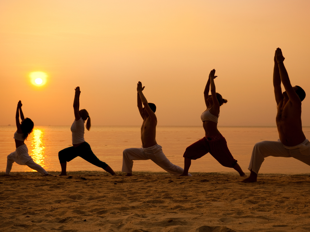 Yoga-übende bei Sonnenuntergang am Strand in ihrer Silhouette. 