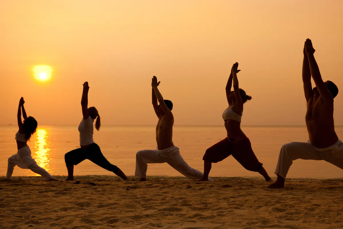 Yoga-übende bei Sonnenuntergang am Strand in ihrer Silhouette.