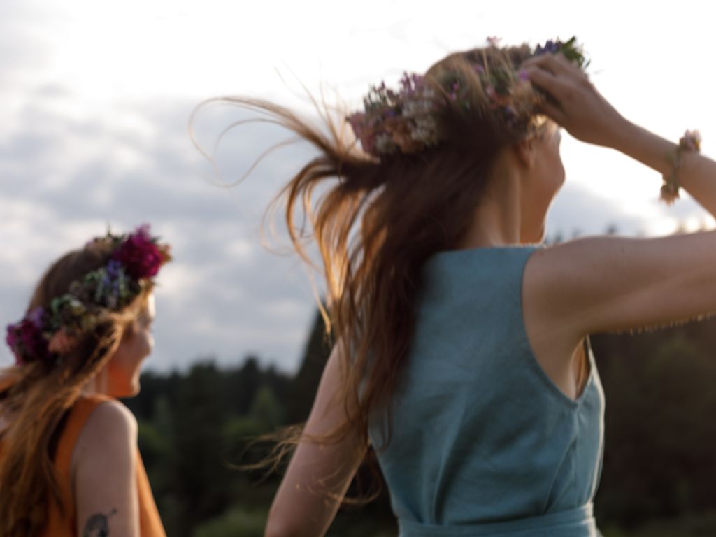 Zwei Frauen mit Blumenhaarkränzen und wehendem Haar